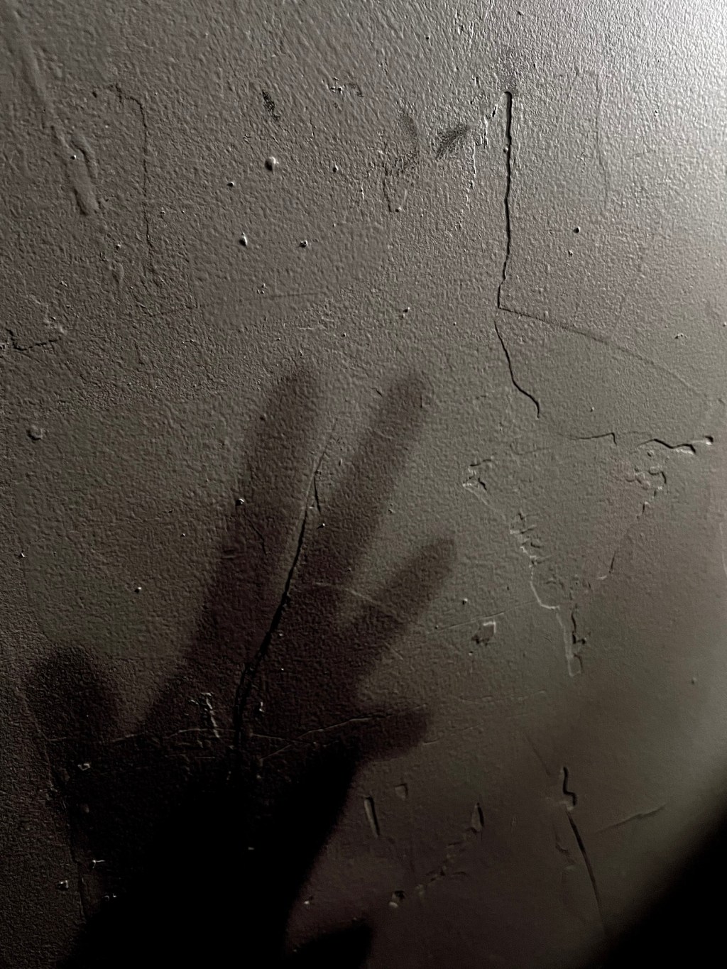 Shadow of a hand on a wall, reaching out